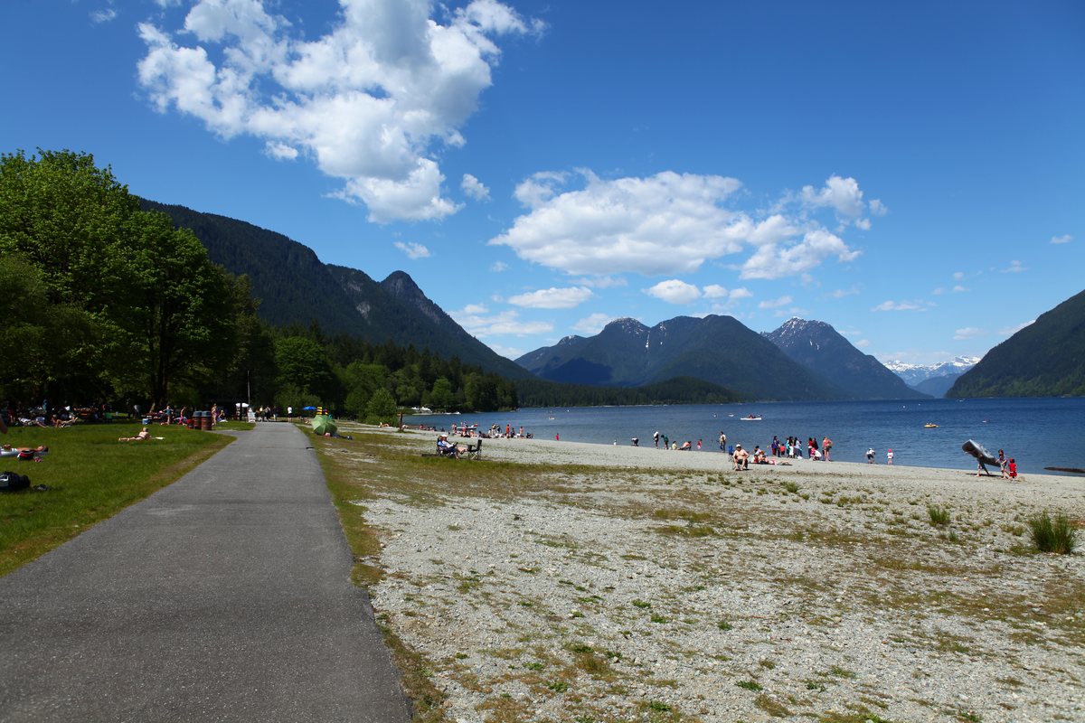 A paved path along the beach at Alouette Lake, with forested mountains across the water.