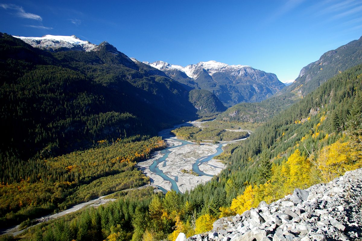 The braided Squamish River running between forested slopes, with snow on the peaks of the upper valley.