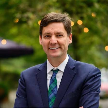 Portrait of David Eby, Premier of British Columbia, treated in the house style: desaturated and lifted in contrast, with an orange tone laid over it and a vignette darkening the right side of the frame.