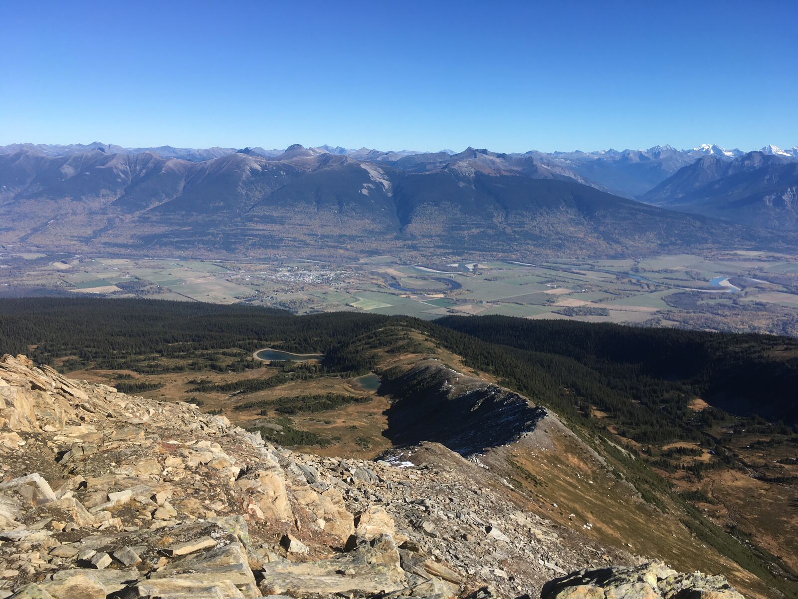 McBride and the farmland of the Robson Valley seen from the rocky summit of Mount Lucille, with the Rocky Mountains beyond.