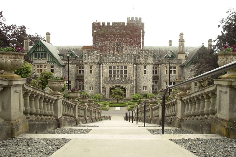 Hatley Castle, a stone mansion with a crenellated tower, seen from the top of a long formal stairway with stone balustrades.