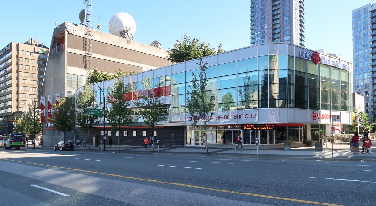 The glass-fronted CBC Regional Broadcast Centre on Hamilton Street in Vancouver, with CBC Radio-Canada signs and satellite dishes on the roof.