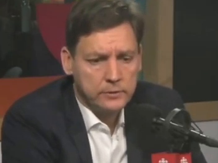 David Eby, eyes lowered, at a CBC microphone.