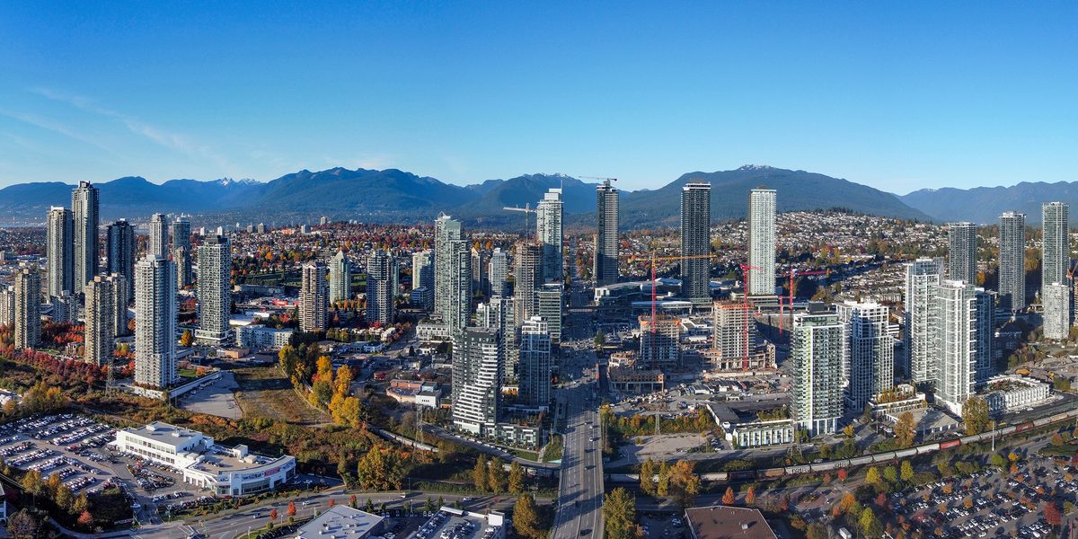 Towers rising around Brentwood Town Centre in Burnaby, with the North Shore mountains behind under a clear sky.