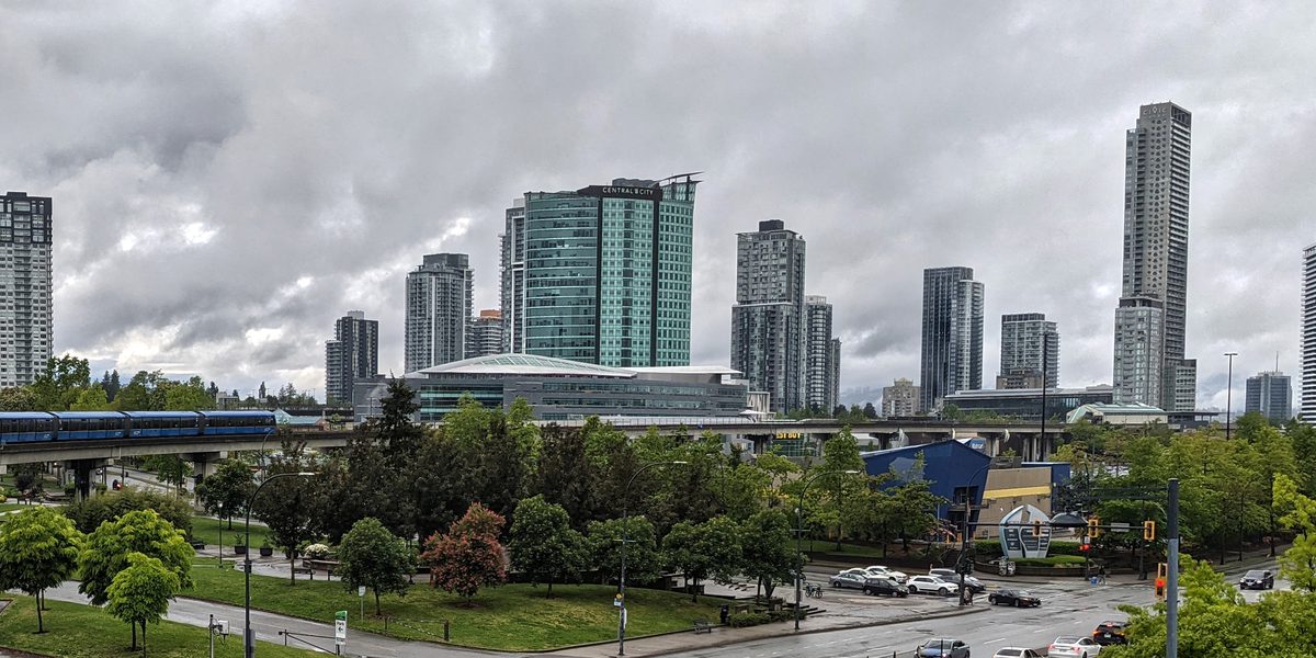The Surrey City Centre skyline seen from King George station in 2025: towers under construction, cranes and the SkyTrain guideway.