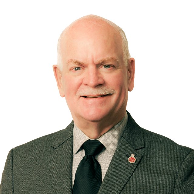Garry Begg, in a dark suit and tie, smiling.