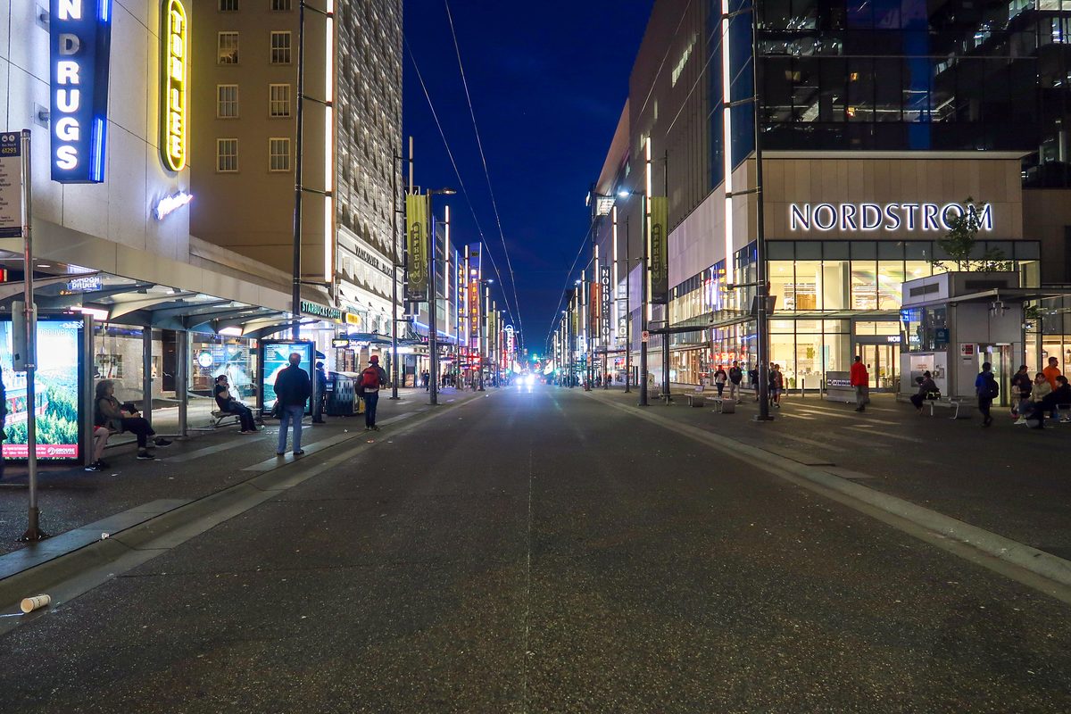 Granville Street in downtown Vancouver at night, shop fronts lit on both sides of the road.